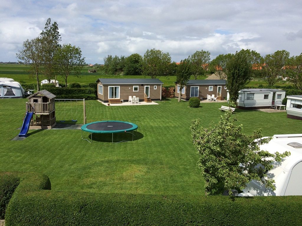 Speelveld met trampoline, chalets erachter
